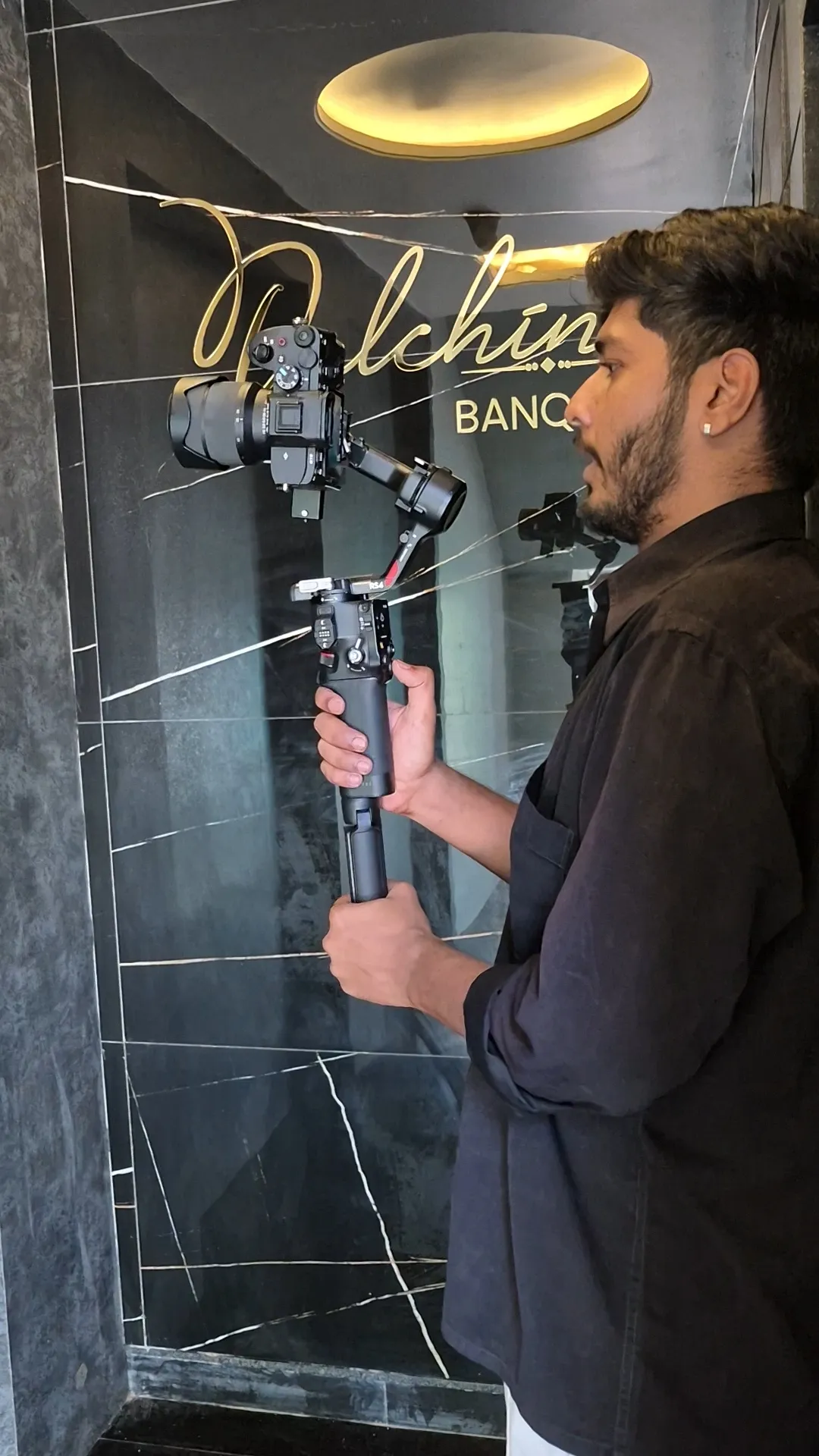 Sahil operating a camera on a handheld gimbal stabilizer at a venue entrance